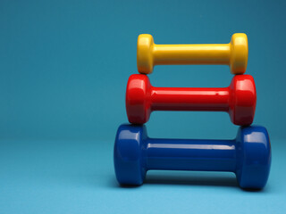 Red, yellow and blue dumbbells on a blue background