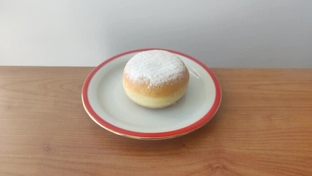Traditional Polish donuts (Paczek) with powdered sugar on white plate.