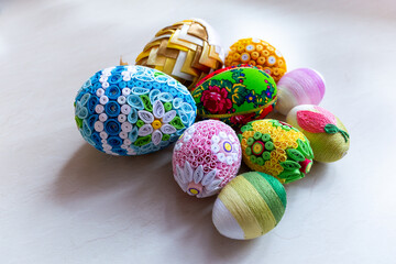 Colorful Easter eggs with floral ornaments, origami decorations and crewel wool against white background, different techniques of Easter eggs decoration, Poland.