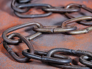 Old rusty link chain on an orange grunge background
