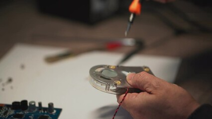 a man with a screwdriver collects a video card fan. High-quality shooting in 4k format