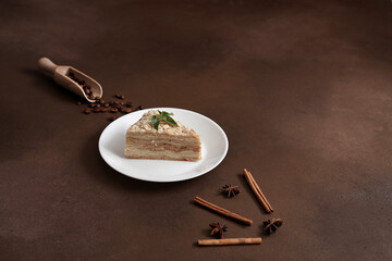 Layered Cake with cream Napoleon with mint on Brown background. A cinnamon stick, badyan, coffee...