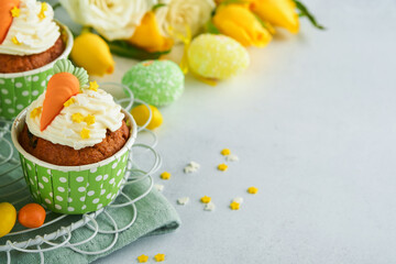 Obraz na płótnie Canvas Carrot cake cupcakes for Easter. Carrot cupcakes with cream cheese frosting decorated with tiny marzipan carrots on white background. Happy Easter and spring holiday concept. Holydays homemade dessert