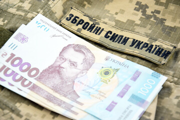 Ukrainian UAH banknotes against the background of a military pixel, the uniform of the military forces of Ukraine.