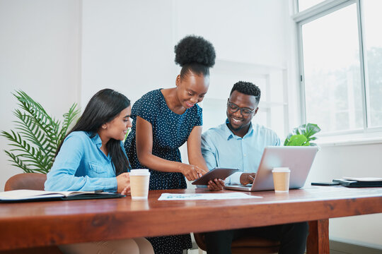 Black woman stands and shows colleagues report on digital tablet