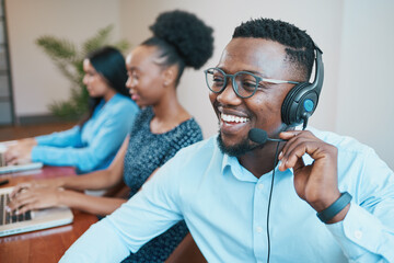 An attractive Black man speaks to client on headset remote call, smiling