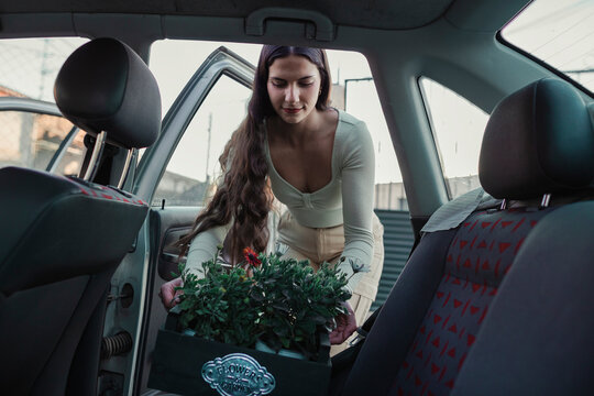 woman unloading some flowers she has bought into her car