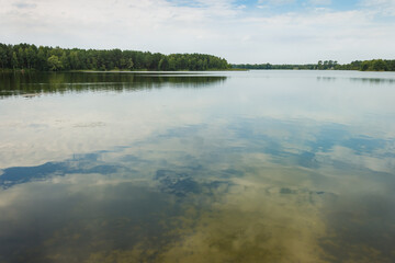 Landscape with a forest lake. Reflection of clouds in the lake. Summer