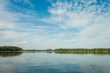 Reflection of clouds in the lake. Landscape with a forest lake on a summer sunny day. 