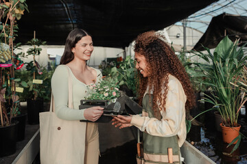 Woman customer paying by credit card at a greenhouse