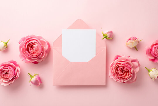 Saint Valentine's Day concept. Top view photo of open pink envelope with paper sheet and peony roses on isolated pastel pink background with copyspace