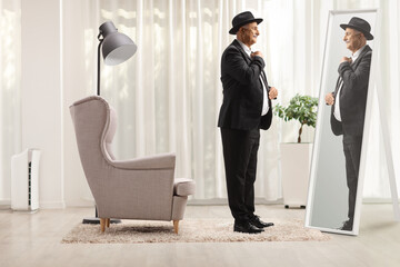 Mature man getting ready and sorting his clothes in front of a mirror at home