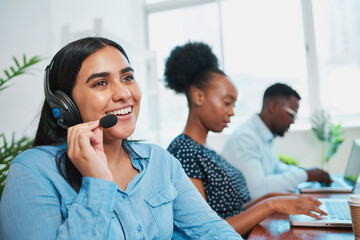 A friendly South Asian woman talks to client on headset, support agent helpdesk