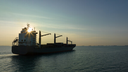 corgo ship container in silhouette and over the sunlight at evening in open sea. aerial view