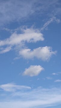 Vertical video of white clouds against a blue sky on a sunny day