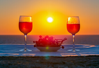Two glasses of wine and grapes at sea sunset