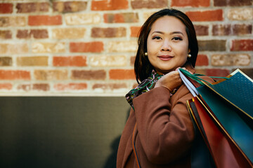 Happy Asian woman with shopping bags looking at camera.