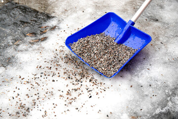 Gravel used on slippery streets roads. Person scattering gravel sand on footpath to reduce...