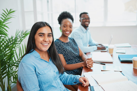 Portrait of diverse team sitting in a row at boardroom table, young women - Powered by Adobe