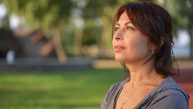 Side view beautiful redhead Caucasian woman opening eyes admiring sunset turning looking at camera. Portrait of confident attractive lady posing in slow motion at sundown in park
