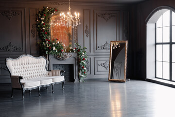 Black room interior with a vintage sofa, chandelier, mirror and fireplace decorated with flowers