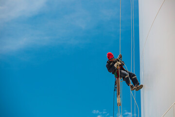 Closeup male worker swings on tank male worker height roof tank knot carabiner rope access safety