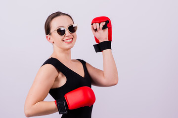 Seductive female boxer with athletic beautiful figure in black swimsuit gloves on gray background