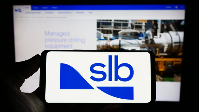 Stuttgart, Germany - 03-09-2023: Person holding cellphone with logo of oilfield company Schlumberger Limited (SLB) on screen in front of business webpage. Focus on phone display.