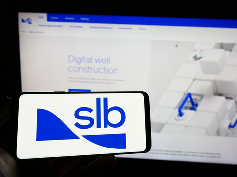 Stuttgart, Germany - 03-09-2023: Person holding mobile phone with logo of oilfield company Schlumberger Limited (SLB) on screen in front of web page. Focus on phone display.