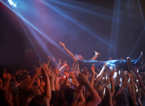 Its the fans who carry the stars. A stage diver being carried across the audience at a rock concert.