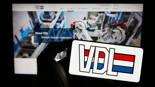 Stuttgart, Germany - 03-09-2023: Person holding cellphone with logo of Dutch manufacturing company VDL Groep B.V. on screen in front of business webpage. Focus on phone display.