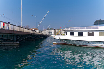 Stern of white paddle steamer at Lake Geneva at Swiss City of Geneva with famous Mont Blanc Bridge on a sunny winter day. Photo taken March 5th, 2023, Geneva, Switzerland.