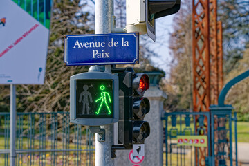 Green light of pedestrian traffic light with street name sign Avenue de la Paix at Swiss City of...