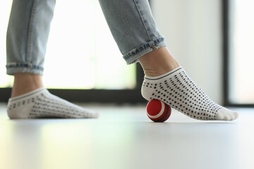 Woman does exercises with ball for prevention of flat feet at home.