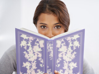 Interesting read. Portrait of a young woman peering over a book.