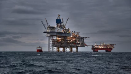 Küchenrückwand glas motiv Picture of offshore oil and gas production in the sea in stormy weather at dusk. Jack up, semi submersible rigs crude oil production in ocean. © Igor Hotinsky