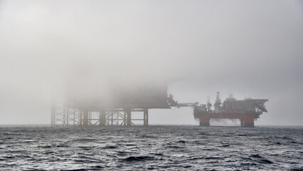 Offshore crude oil production installation covered in fog in the ocean. Jack up drilling rig, semi submersible platform covered in fog in the sea. 