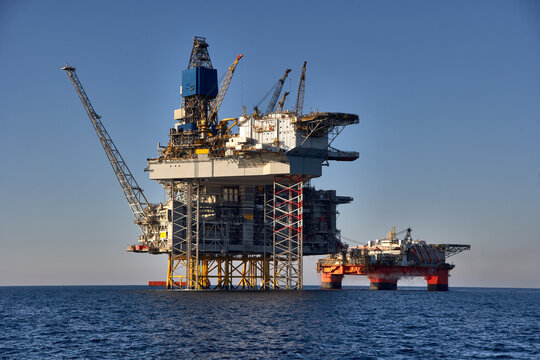 View of offshore oil and gas installation in a sunny day in sea. 
Jack up, semi submersible rigs crude oil production in ocean.