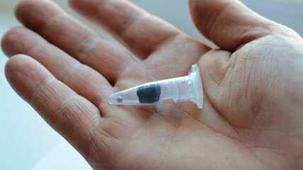 a transparent plastic capsule with an absorbent pad and one seed inside for the secure transport of plant material, lying in the palm of a person close-up