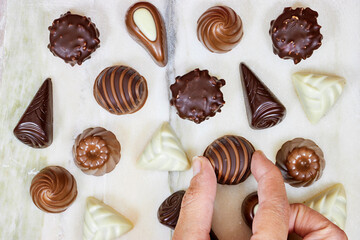 hand holding one piece of premium chocolate sweets  on marble background
