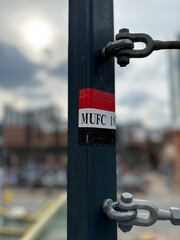 Sticker on a lamp post with a blurred background. Manchester City centre. 