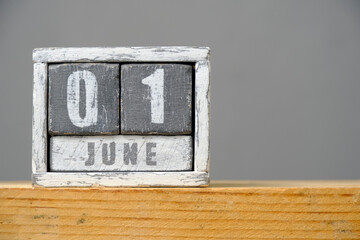 Calendar for June 01 made of wooden cubes standing on shelf on gray background.With an empty space for your text.