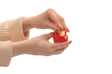 Red bottle of perfume in woman hand with red nails isolated on a white background.