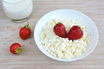 A bowl of cottage cheese with ripe garden strawberries on top isolated