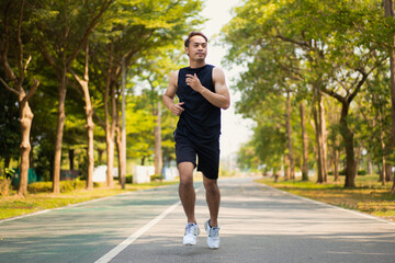 happy young Asian handsome man enjoys his running  in city public park during a summer day, sporty guy spend quality time on weekend jogging outdoor in nature for healthy and active lifestyle