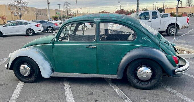 Old retro green and white Volkswagen Bug in the parking lot during the daytime