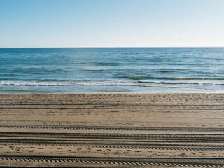 Fototapeta premium Tire tracks and footprints on a sandy beach on a sunny day in Marbella, Spain