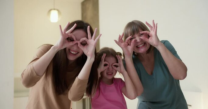 Photo of three childish positive people holding hands fingers make binoculars for fun