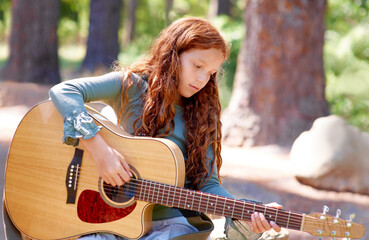 Shes a skilled musician, despite her age. Cropped view of a young girl playing the guitar outdoors.