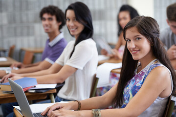 Getting the grades she wants. a happy young college student working at a laptop in class.